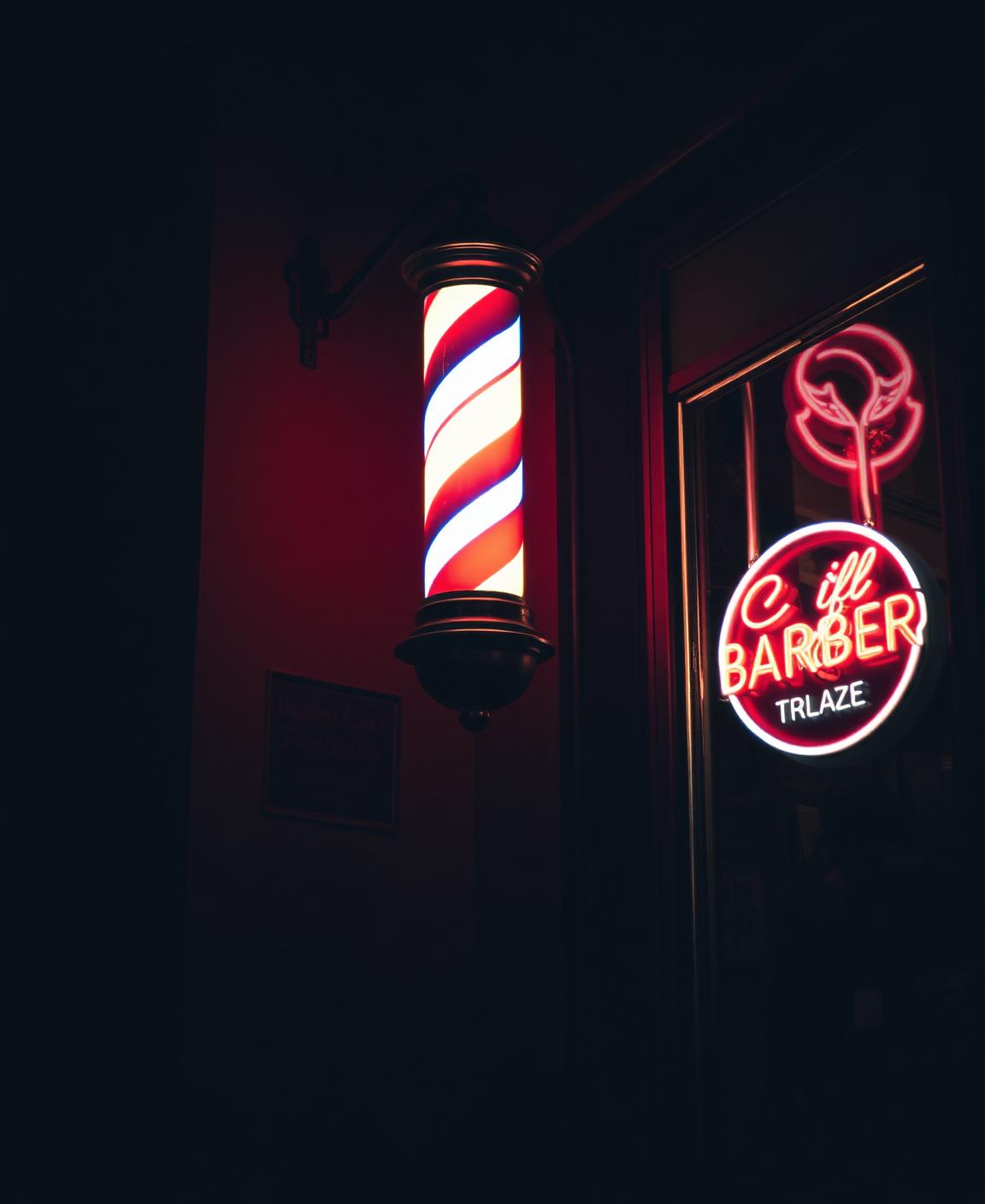 Glowing barber pole outside the Suave storefront at night